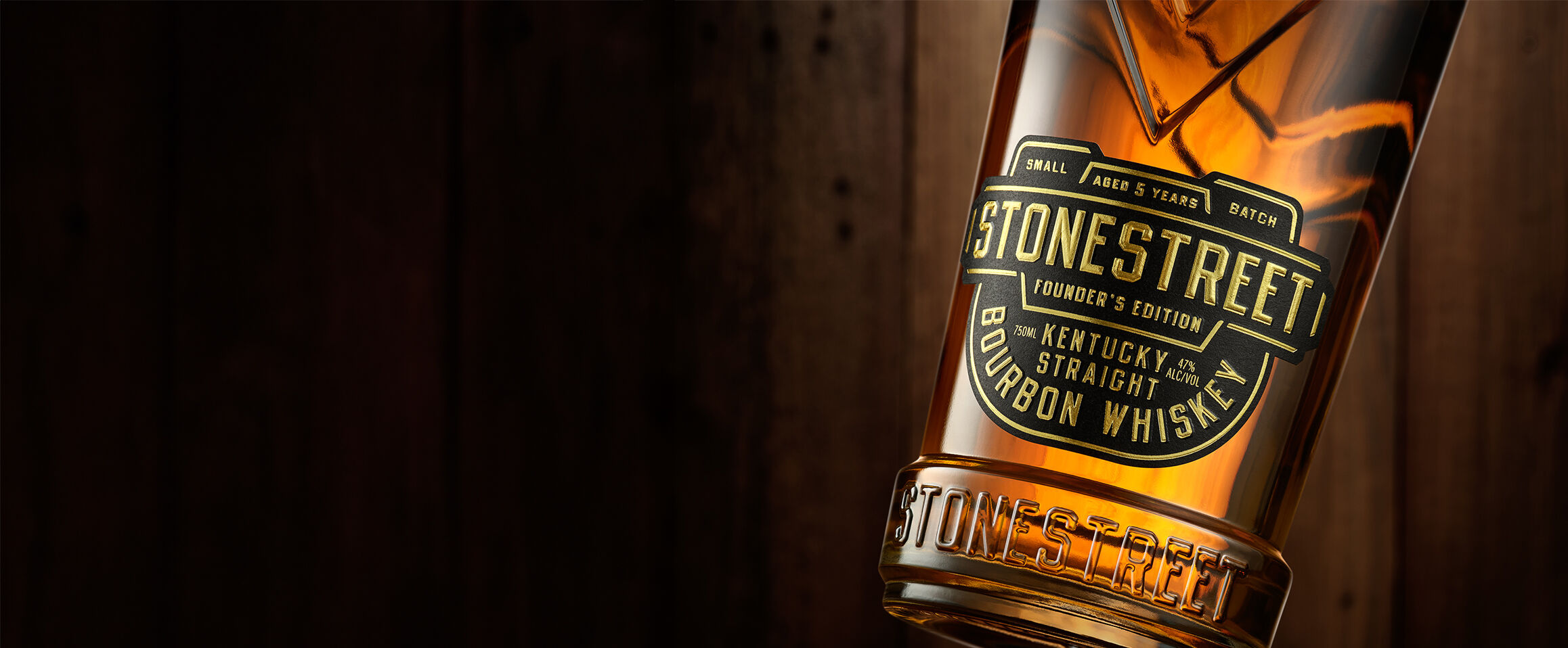 A bottle of Stonestreet Bourbon on a barrel with barrels in the background.